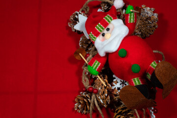 red christmas background with many pine nuts and stars tied to a rope and a santa claus on top and space to add text