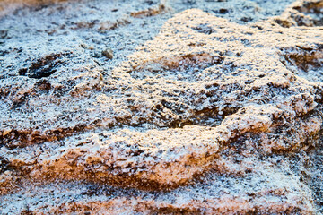 Stones covered with snow. Abstract surface and Backdrop texture. Relief stairs. Natural material and sun rays. 