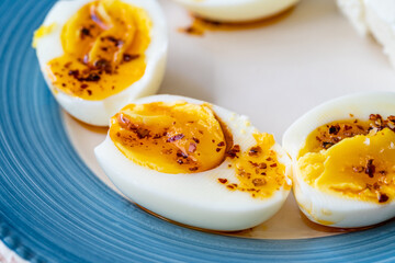 Boiled Eggs with Hot Butter Chili Pepper Sauce. Half Cut Style in Breakfast Plate.
