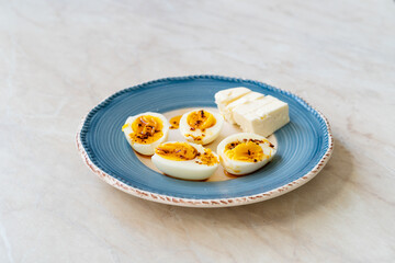 Boiled Eggs with Hot Butter Chili Pepper Sauce. Half Cut Style in Breakfast Plate with Cheese.