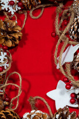 red christmas background with a frame of many pine nuts and stars tied to a rope and space to add text