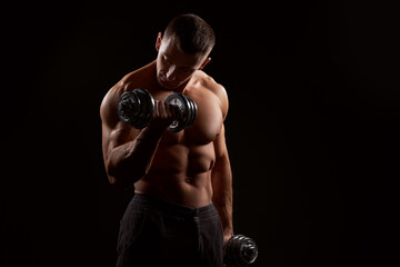 Naklejka na ściany i meble Shirtless muscular man holding dumbbells against of black background.Studio shot