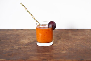 Natural products concept.Glass plum juice or smoothie with paper straw on wooden natural table.