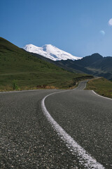 Fototapeta premium An asphalt road leading to the mountains. Picturesque landscape. Postcard