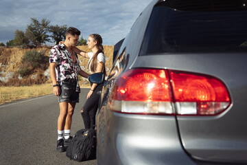 Couple leaning on car while waiting for tow truck