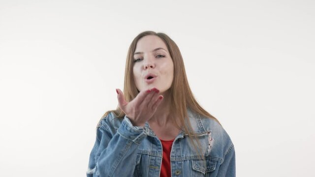 Young beautiful woman sends an air kiss and looks at the camera. White background.