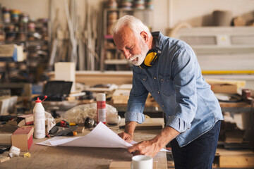 Carpenter reading the project blueprints confidently
