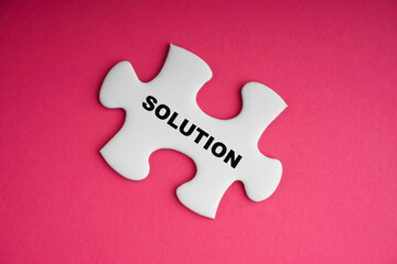 SOLUTION text with white jigsaw puzzle on pink background. Business and motivation concept