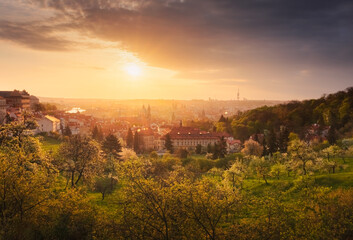 A beautiful spring view of Prague at sunrise from Petrin hill. Prague Castle and St. Vitus Cathedral on the left and a golden rising sun in the background.