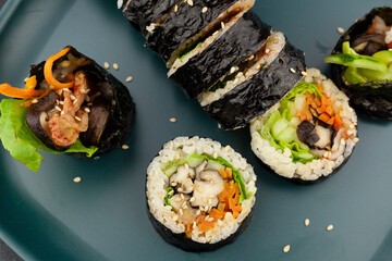 Top view plated Korean traditional sliced kimbap made with shiitake mushrooms, carrot, lettuce, rice and seaweed and sesame seeds.  