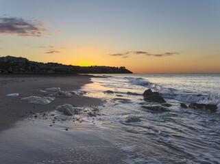 Sunrise at the beach with waves and rocks