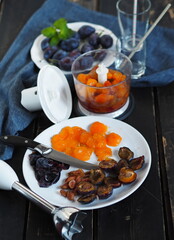 The process of making cream juice from natural plums or smoothies using a mixer.Dark background with a blue ripe plum on a blue napkin.