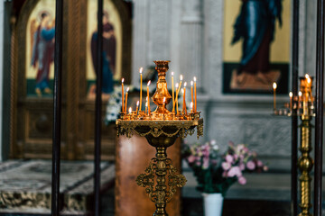 Interior of Christian church with burning candles. Burning candles placed on golden ornamental candlestick inside traditional Christian church with blurred background