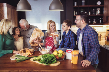 Three generation family in kitchen preparing lunch, having fun