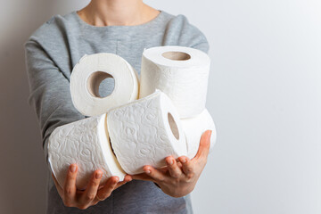 woman holds many rolls of toilet paper. Close-up without a face, studio, white background.