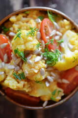 Cauliflower curry with cherry tomatoes on a rustic background