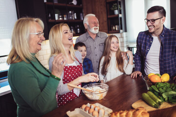 Three generation family in kitchen preparing lunch, having fun