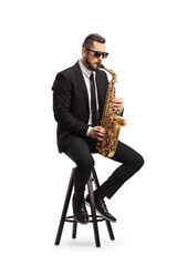 Male musician in a black suit playing a saxophone and sitting on a chair