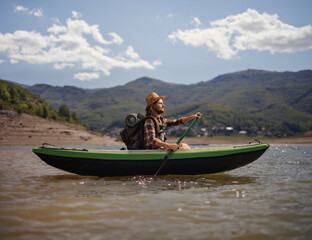 Young male backpacker paddling in a canoe
