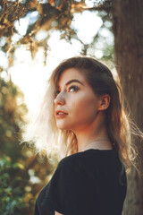 Naklejka premium Cute woman close-up portrait in sunny day outdoor in trees