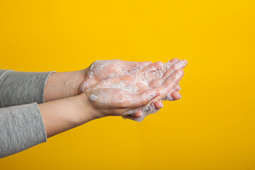 washable hands close-up on a yellow studio background. Proper hand washing as a prevention of viruses .