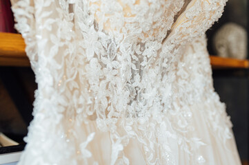 A chic silk wedding dress hangs on a bookcase.