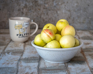 White nectarines in a deep plate on a wooden table simple rustic room