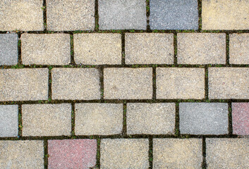 road paved with gray, yellow and brown sidewalk tiles. texture of light gray bricks.