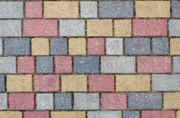 road paved with gray, yellow and brown sidewalk tiles. texture of light colored bricks.