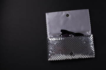 Elegant women envelope bag with silver metallic sequins and fancy sunglasses