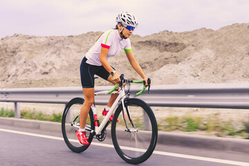 Naklejka premium Young Woman Cyclist Riding Bike on the Mountain Road. Adventure, Healthy Lifestyle, Sport