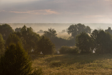 Fototapeta na wymiar Amazing scenic early morning misty landscape just before sunrise. Aerial view photography of orange sky, horizon line, meadows and forests covered with thick white fog.