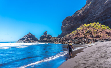 A young tourist enjoying summer by the sea on some rocks in Playa de Nogales in the east of the Island of La Plama, Canary Islands. Spain