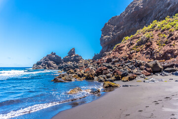 A young tourist enjoying summer by the sea on some rocks in Playa de Nogales in the east of the Island of La Plama, Canary Islands. Spain