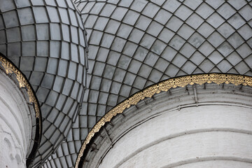 Traditional russian churhe domes made of grey metal scales with golden decoration close up