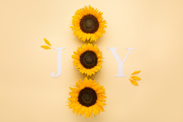 Word Joy. Autumn greeting card invitation. Beautiful fresh sunflowers with leaves on yellow background.