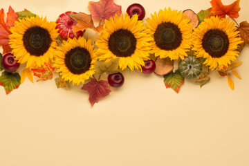 Autumn holiday composition. Sunflowers, dried leaves, pumpkins, apples and rowan berries on yellow background.