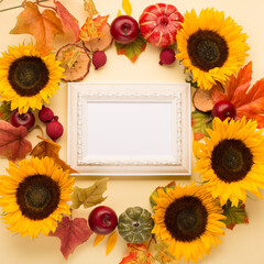 Garland of  Sunflowers, dried leaves, pumpkins, apples and rowan berries on yellow background.