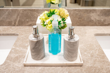 Blue alcohol gel or hand sanitizer with soap and lotion pump bottles on granite lavatory countertop in bathroom. washing hand with personal care concept