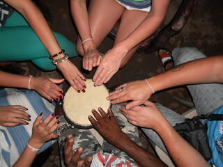 hands of white and black people playing the drum together
