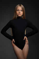 Beautiful girl teenager blonde in a black bodysuit in the studio