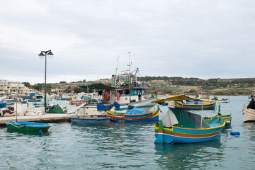Naklejka na ściany i meble The traditional maltese luzzu boats in the harbor of fishing village Marsaxlokk in Malta 