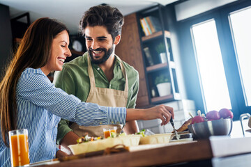 Portrait of happy couple cooking together in the kitchen at home.