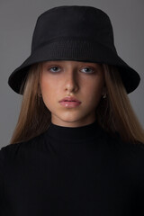 Portrait of a beautiful blonde teen girl in a black bodysuit and hat