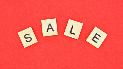 word SALE made of wooden letters on red background.Top view. Seasonal sale.