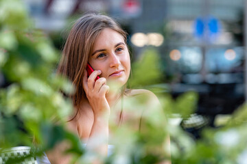 Fototapeta premium joyful young woman talking on smartphone while sitting at street cafe outdoors