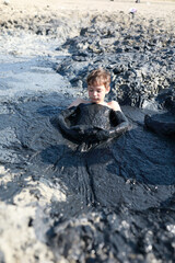 Boy sitting in medicinal mud