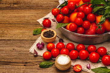 Fototapeta na wymiar Assorted ripe multicolored tomatoes. Young garlic, fresh basil leaves, salt, spices