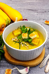 Yellow zucchini cream soup. Healthy vegan (vegetarian) food, crispy toast, sunflower seeds, whole ripe fruits, fresh greens
