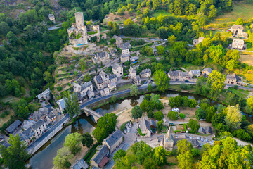 Scenic drone view of medieval village of Belcastel on banks of Aveyron River overlooking fortified Belcastel castle towering above it in summer, France.